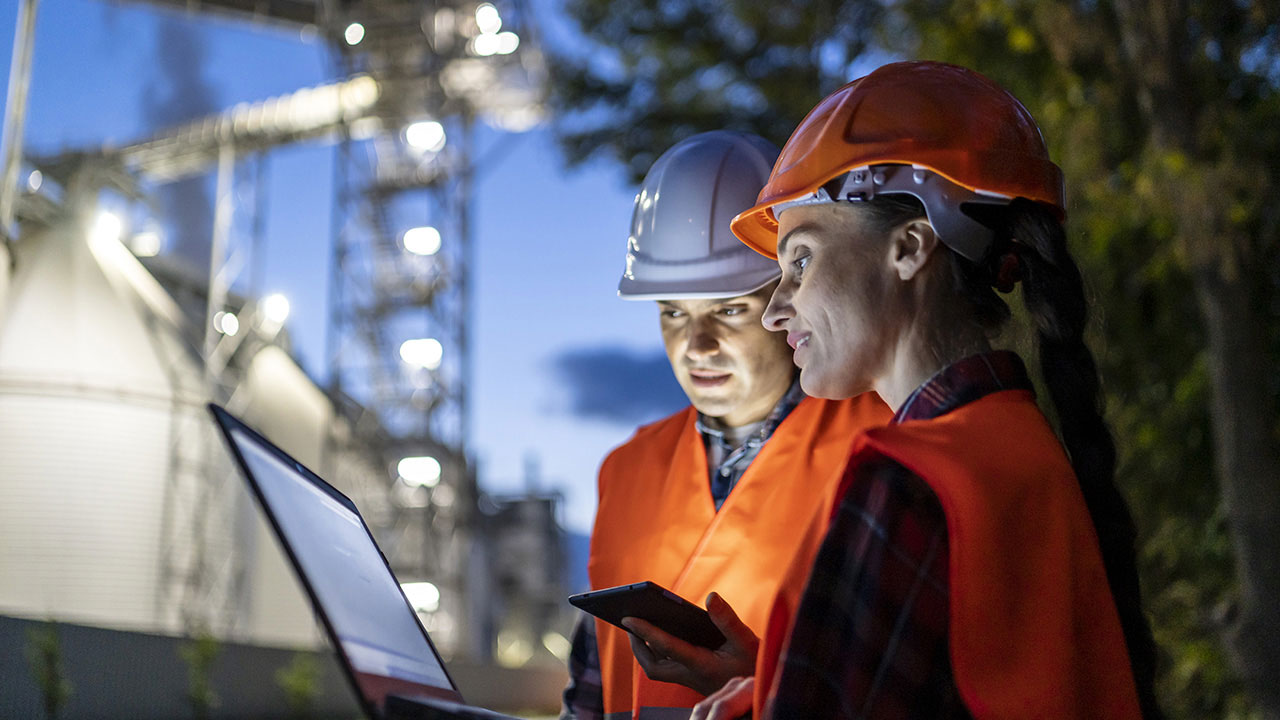 Refinery employees reviewing data on a tablet